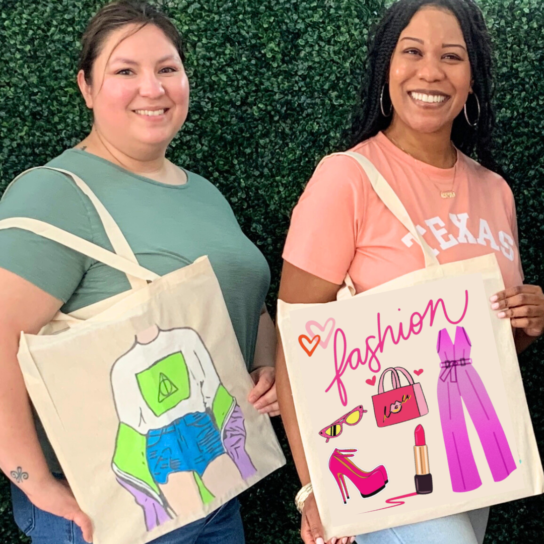 Two women holding tote bags from sip and paint with fashion-themed designs against a green bush background